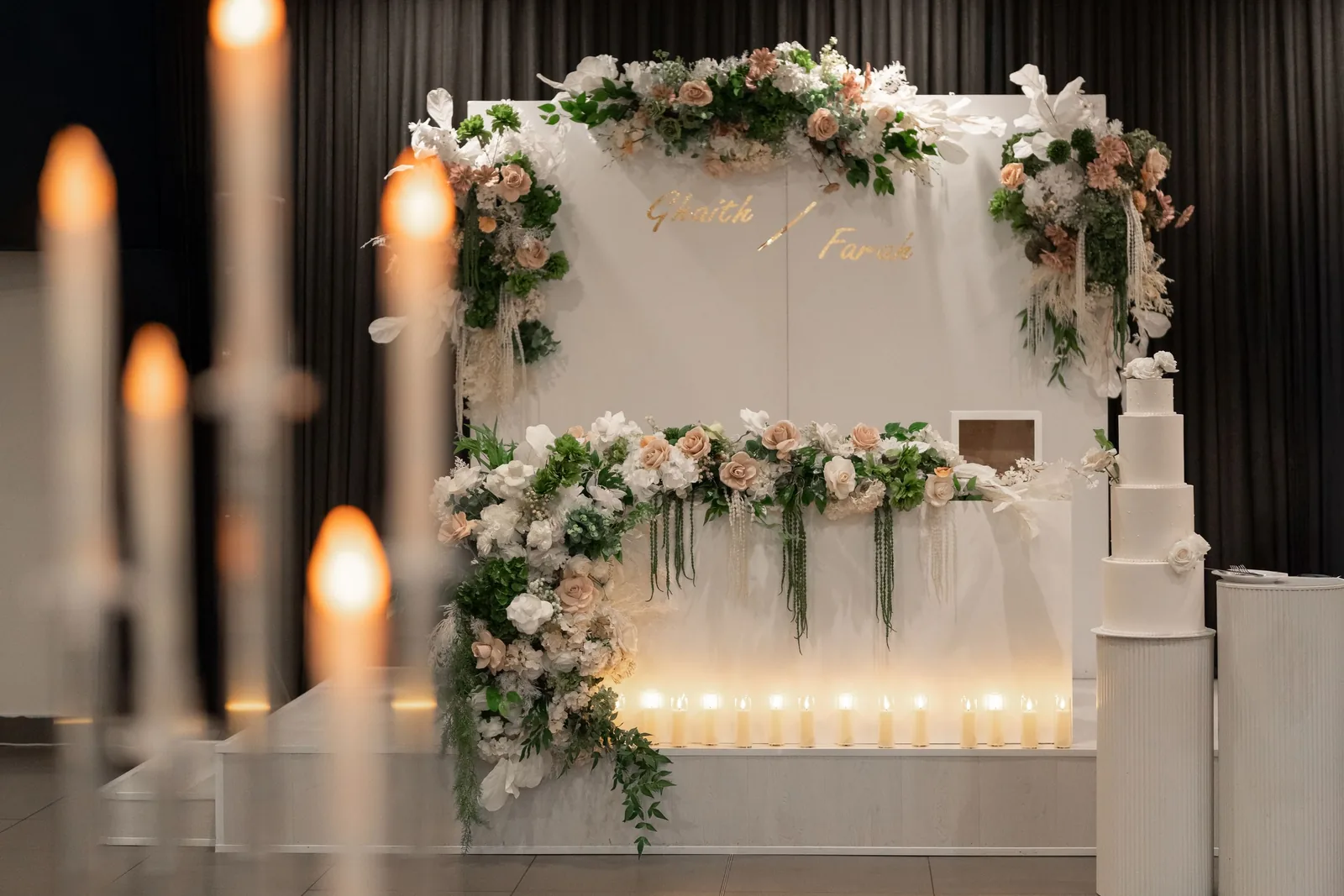 Elegant wedding chuppah adorned with blush pink flowers, greenery, and candles in a modern venue.