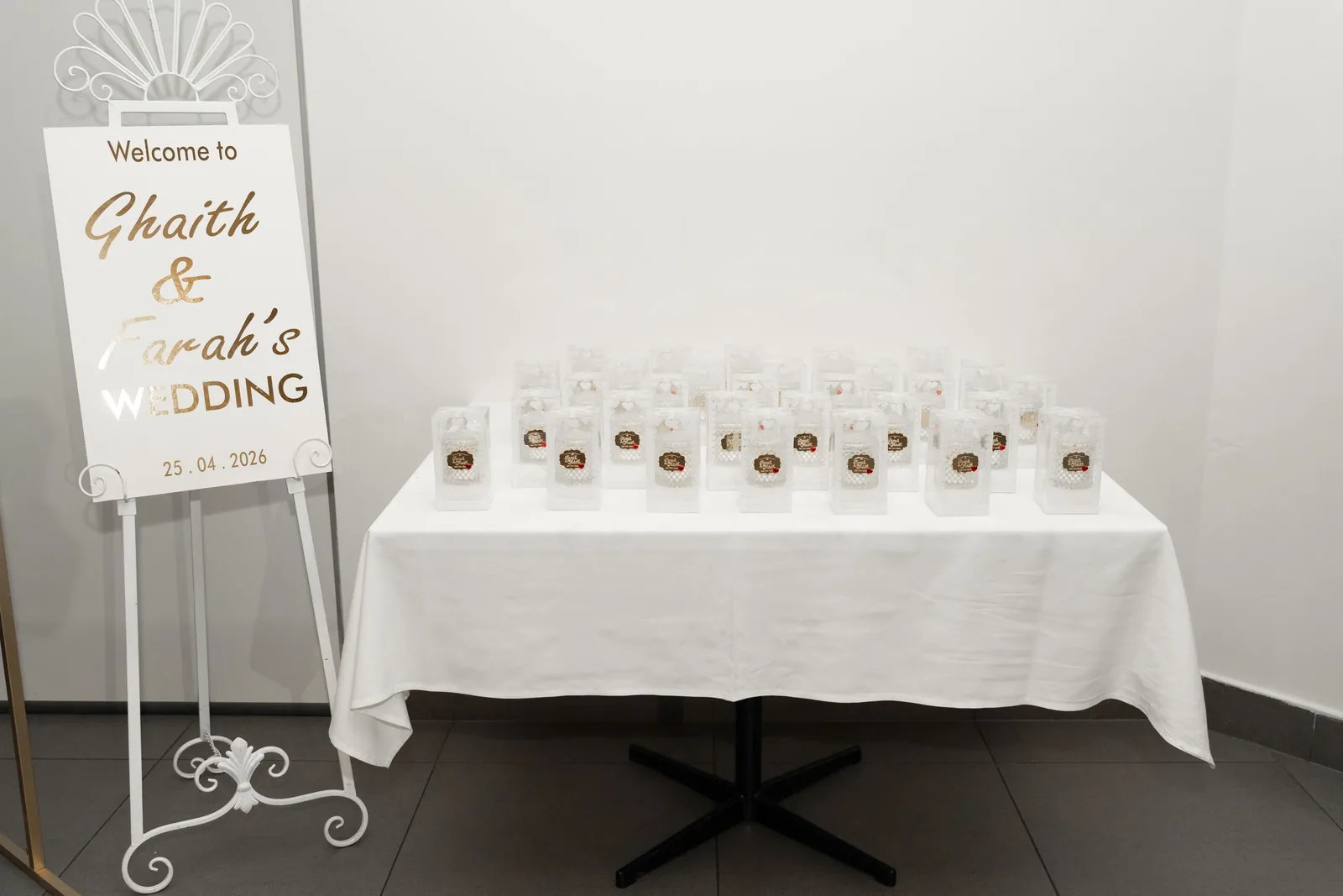 Wedding welcome sign for Ghaith and Sarah displayed beside a table with personalized guest favor bags.