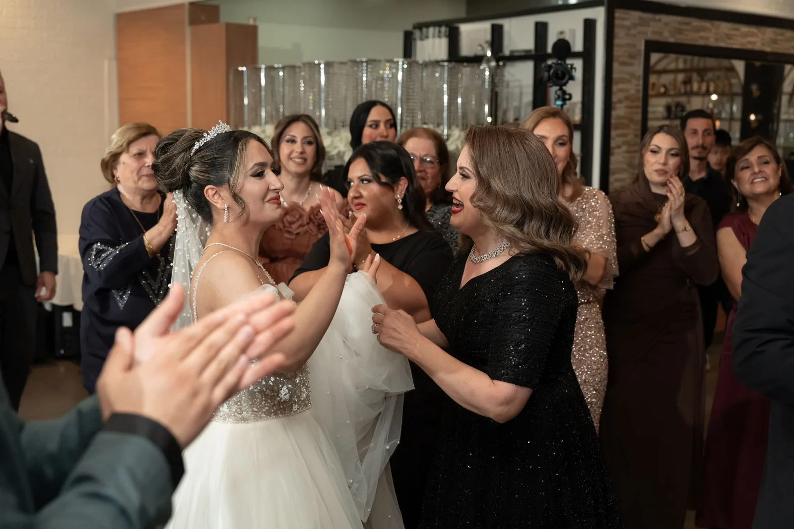 Bride celebrates with female wedding guests who congratulate her warmly at indoor reception.