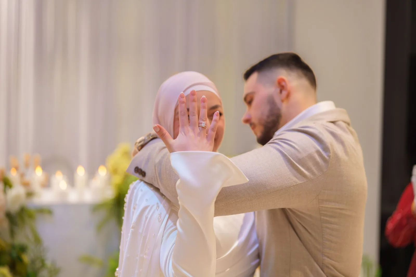 Intimate moment captured during a wedding celebration with soft lighting and floral decorations.