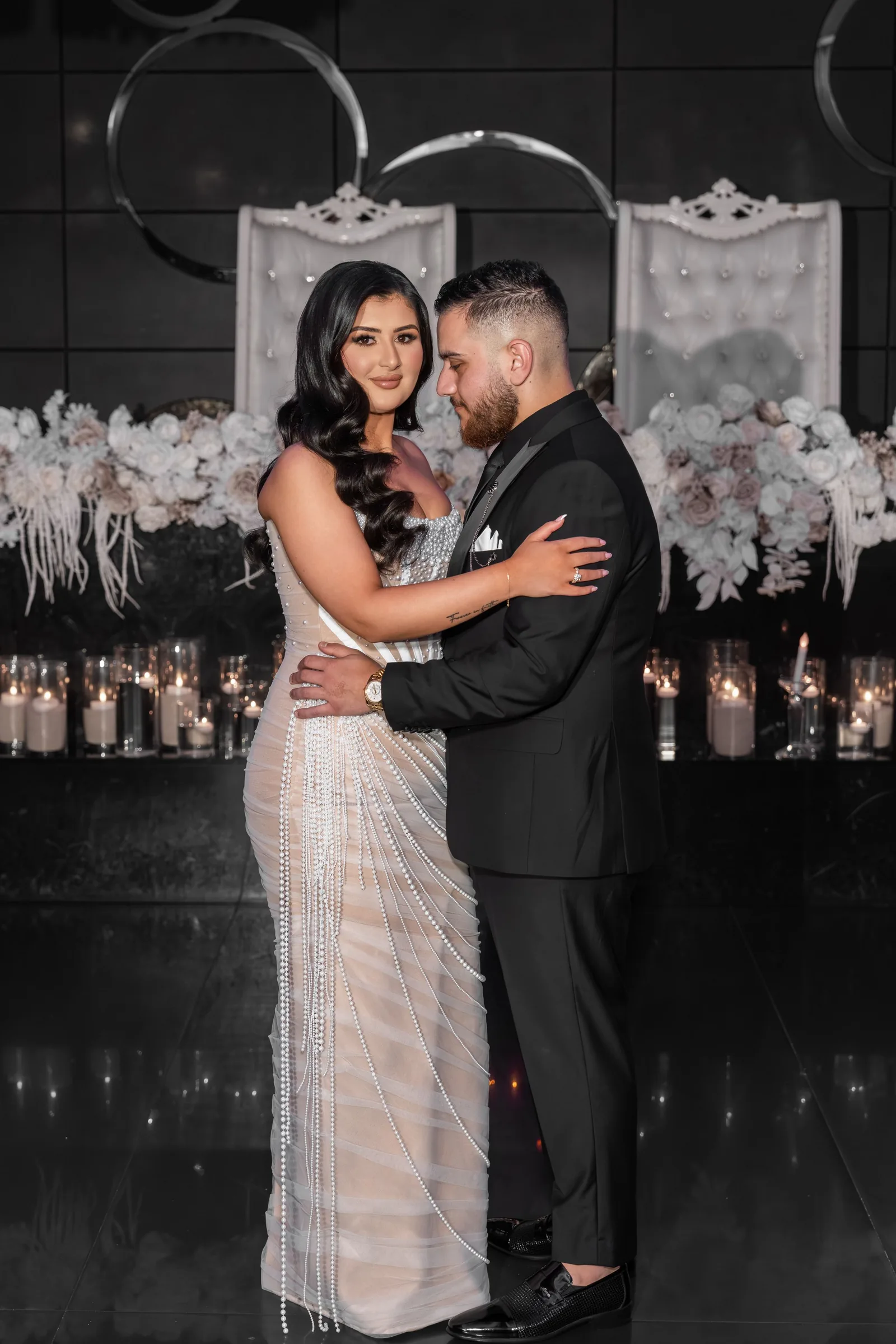 A couple shares their first dance at a wedding reception with romantic lighting and floral decorations in the background.