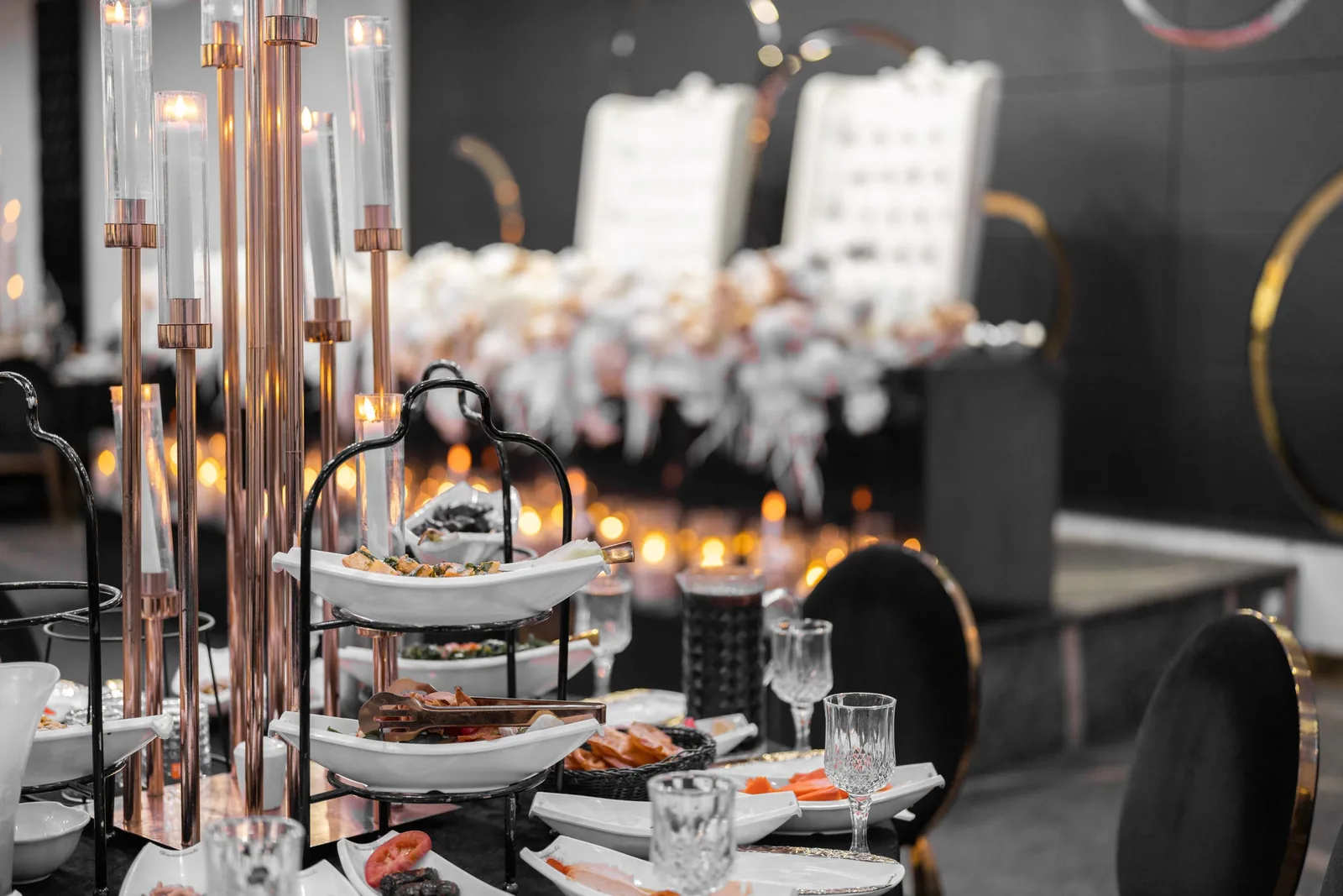 Elegant table settings with rose gold decor and white linens at an upscale wedding reception.