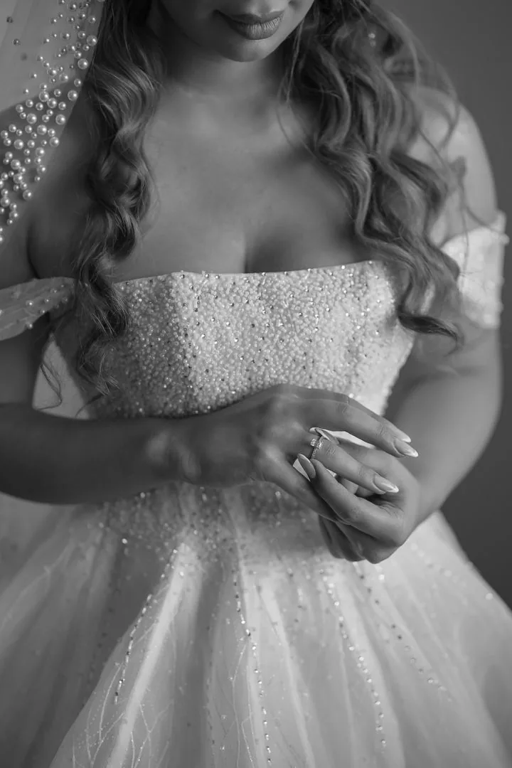 Close-up detail of a sparkly beaded wedding dress bodice and ring.