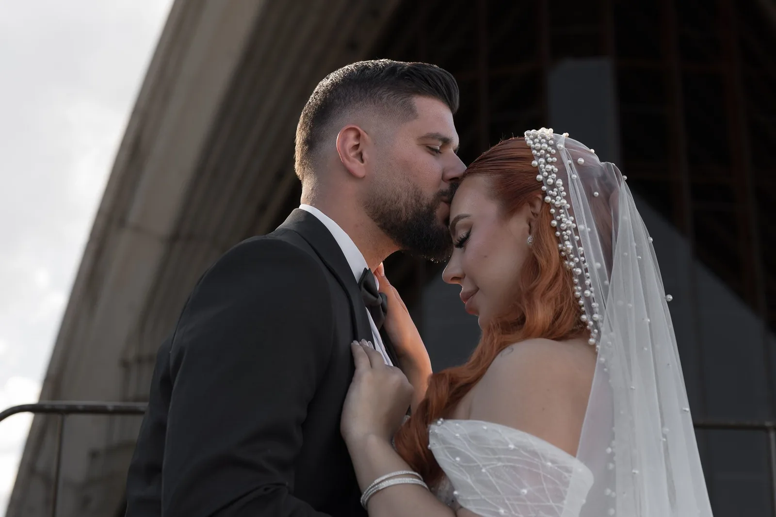 Intimate wedding moment captured in black and white against architectural backdrop.